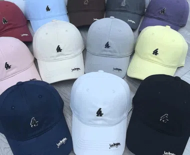 Viele Baseballcaps in Pastellfarben, Dunkelblau, Weiß und Schwarz mit kleiner Stickerei vorne, dicht nebeneinander