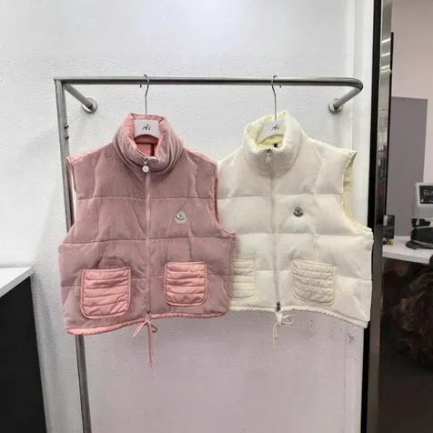 Zwei gesteppte Westen in Rosa und Creme mit aufgesetzten Taschen an einer Kleiderstange